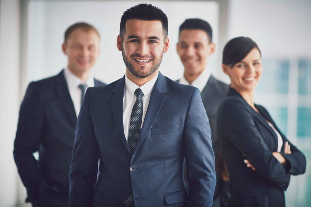 Portrait of confident business partners looking at camera with smiling leader in front